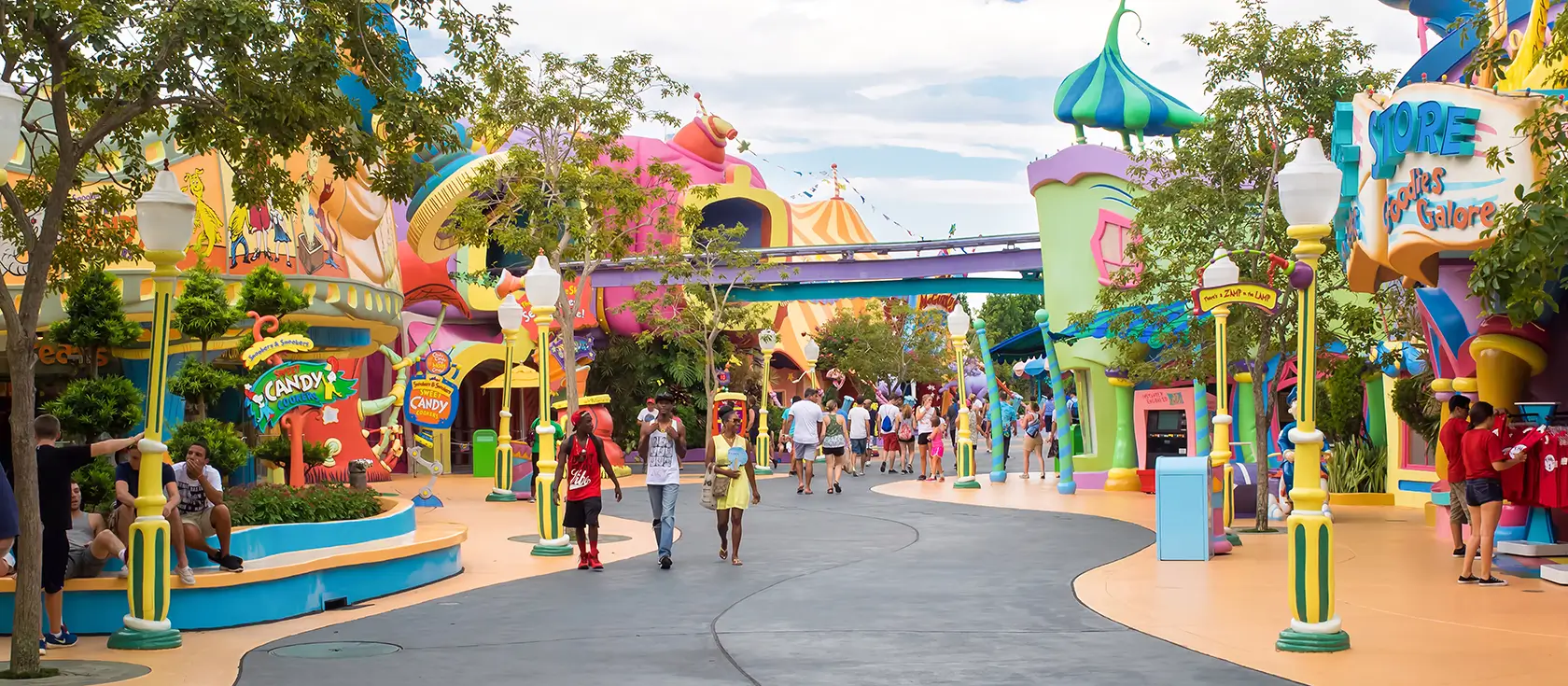 Sun-drenched theme park filled with comfortable crowds enjoying a beautiful day under blue skies.