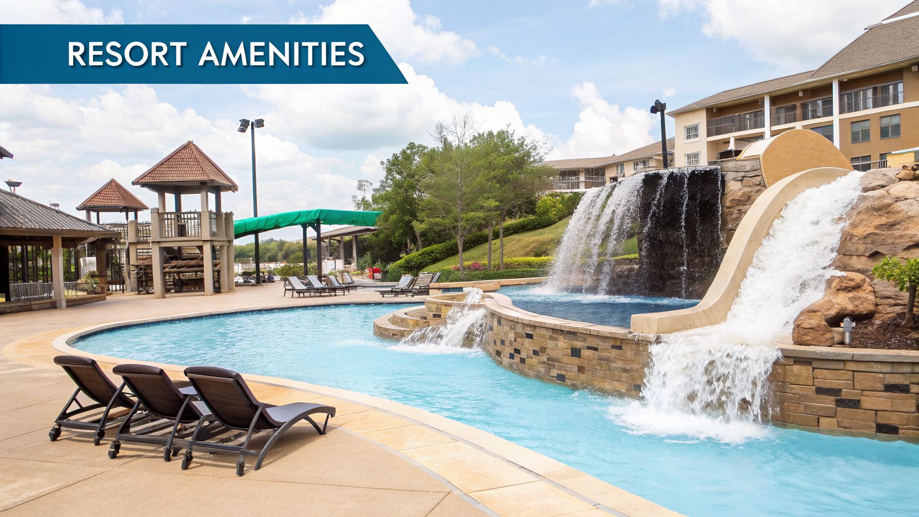 A vibrant resort swimming pool area featuring a thrilling water slide, cascading waterfalls, and comfortable lounge chairs under a blue sky.